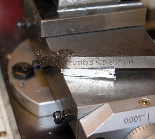 Metal vise with black knob and engraved BP-202-5% COBALT, next to white measuring device.