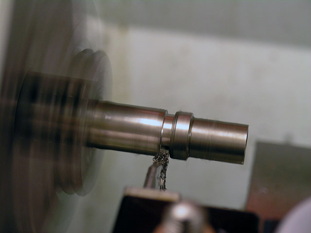 Metal shaft being machined on a lathe.