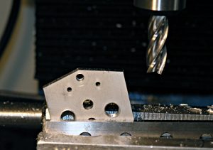 Close-up of a three-flute drill bit or end mill attached to a machine tool.
