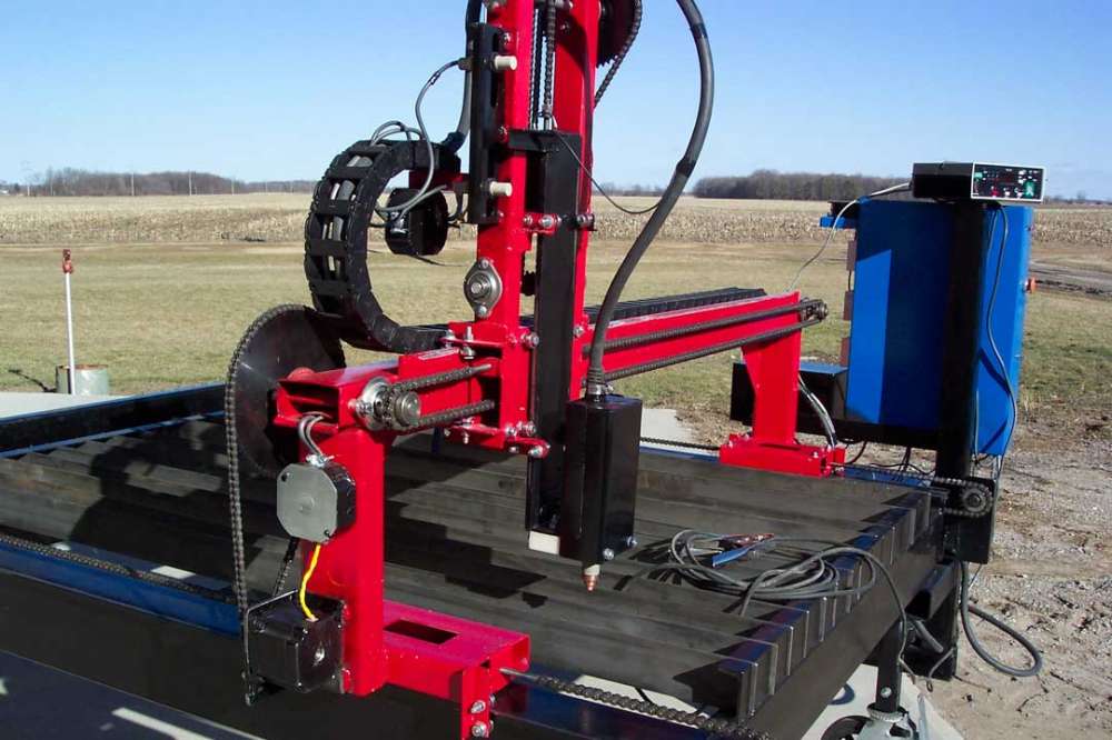 Large outdoor CNC plasma cutter in a rural field setting.