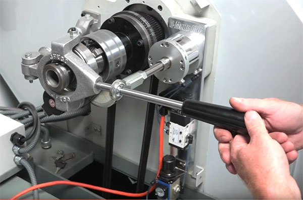 A hand grasping a handle connected to a metal device on top of a machine with various components and wires.