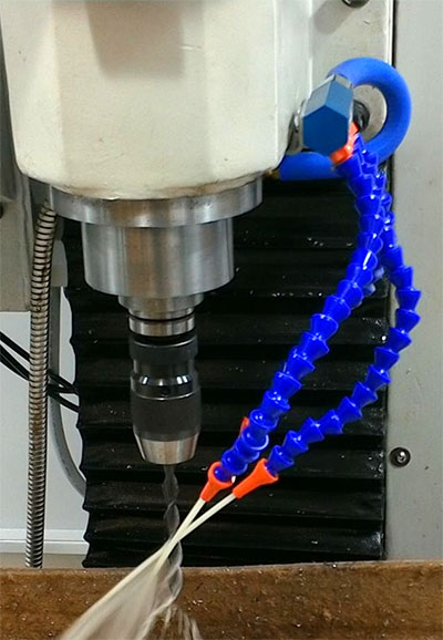 Blue and orange industrial coolant nozzle on machinery.