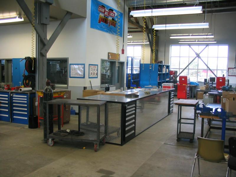 Well-organized school shop with tools and equipment on wooden benches.
