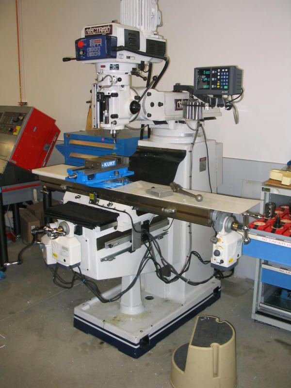 Large industrial machine with control panel and table in a workshop setting.