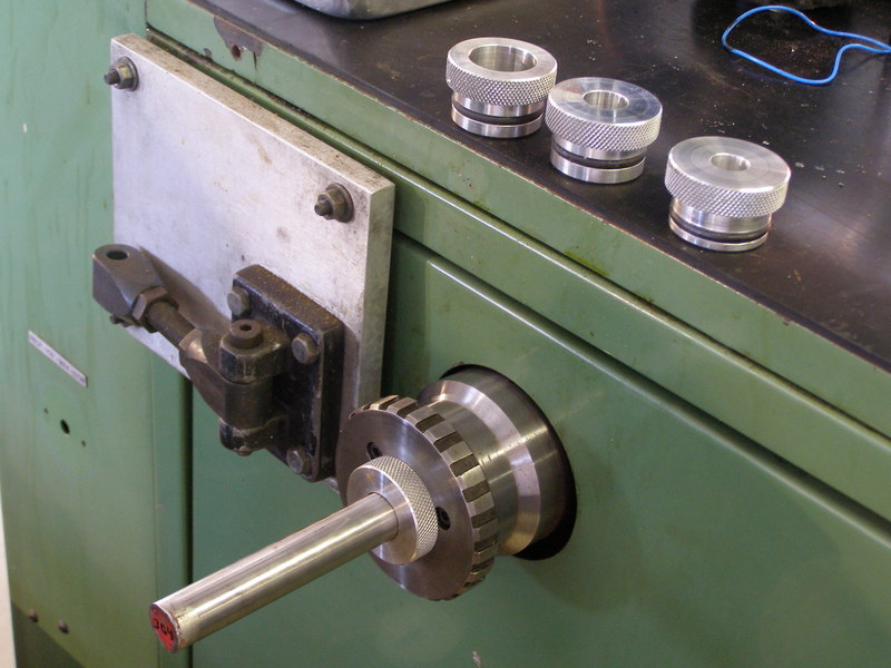 Silver metal parts with knurled edges on a green metal cabinet.