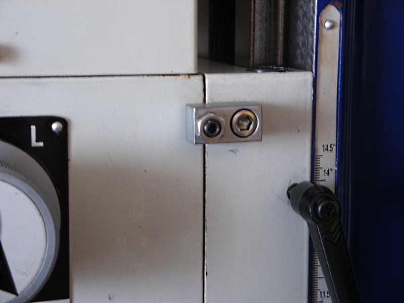 A metal object with two screws, including a silver bracket with two black screws and a small central hole.