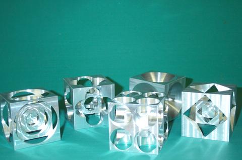 Intricately cut aluminum cubes with varied shapes and holes.