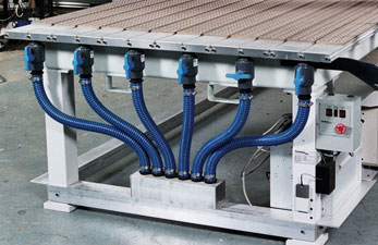 Stainless steel vacuum table with blue hoses and grid-patterned surface.