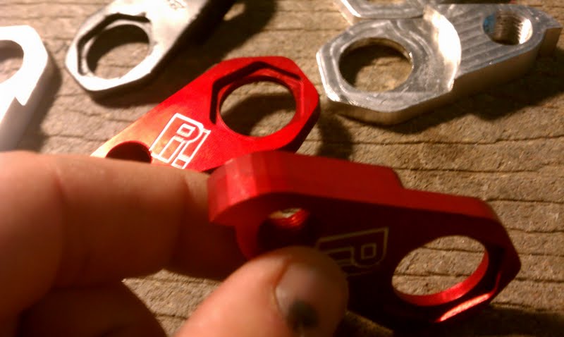 Metallic components in close-up, featuring a red piece with a central hole.