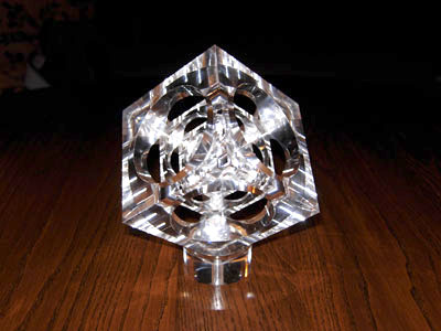 A transparent crystal cube with precise edges on a dark wooden table.