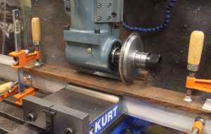 Horizontal milling machine with Kurt Manufacturing vise, featuring a workpiece clamped in place.