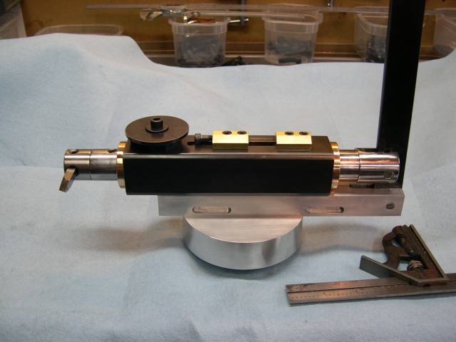 A black and silver metal device with various components attached, placed on a light blue cloth-covered table.