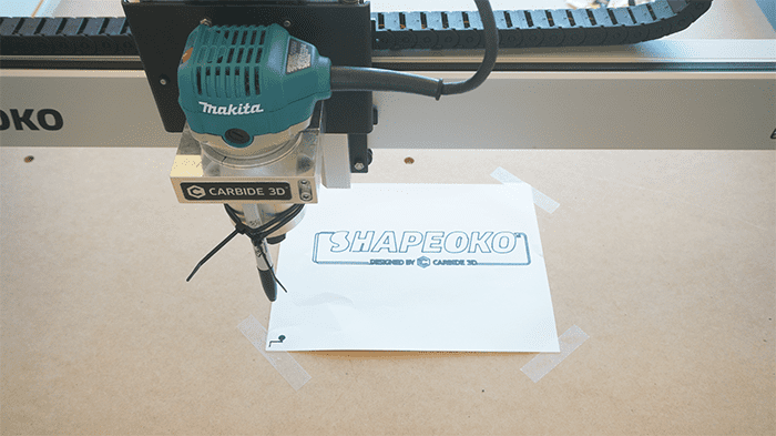 A Makita router with a Makita 3D Carbine mounted on it, set against a light-colored background.