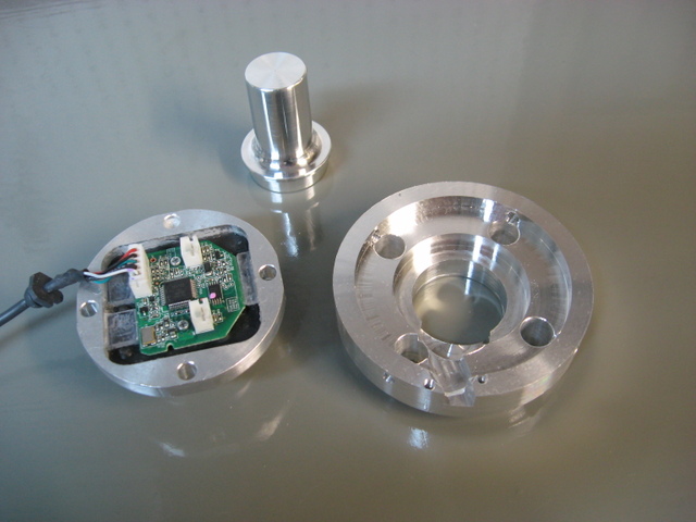 Two metallic components with a green circuit board.