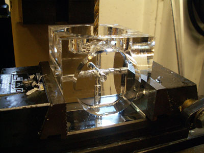 Clear glass object with two holes, on a black metal base with mechanical components.