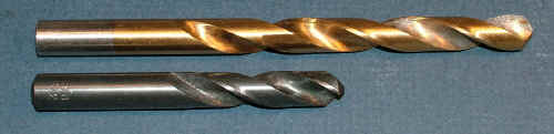 Two drill bits with twisted shafts on a gray background.