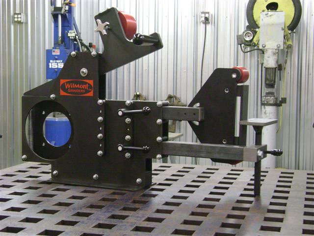 A large black metal Wilmont Ginders grinder with red accents and silver bolts sits on a table in an industrial setting.