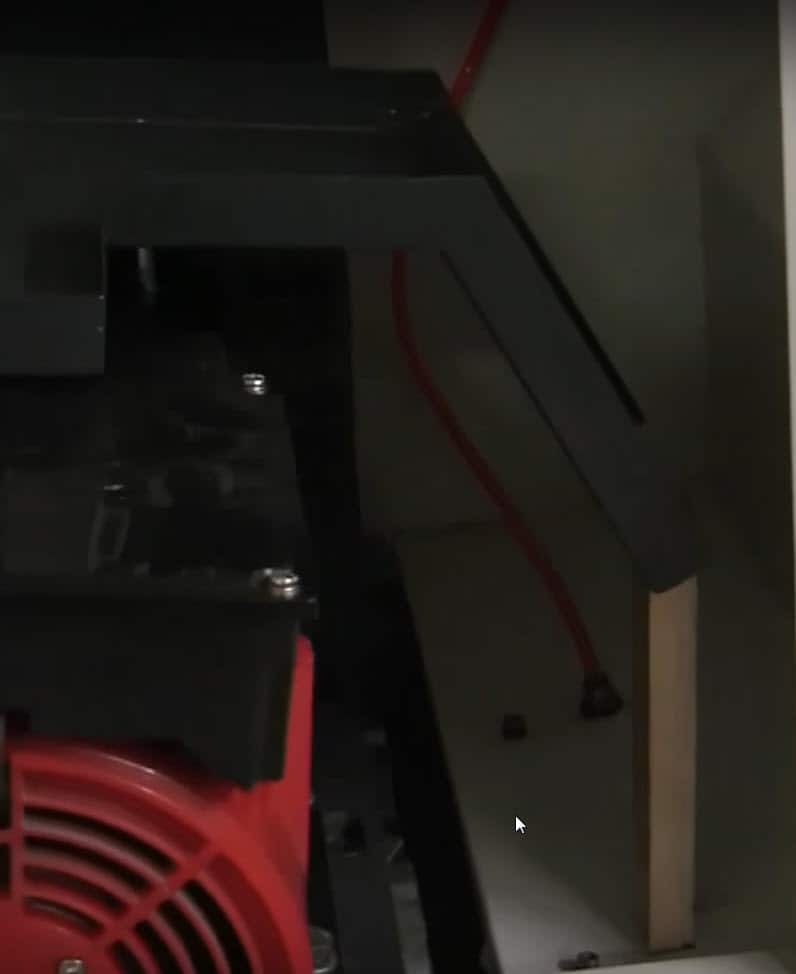 Darkened industrial air compressor unit with red fan and black control panel.