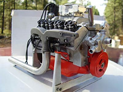 A small red based engine with a silver top and black cord, situated on a white work surface.