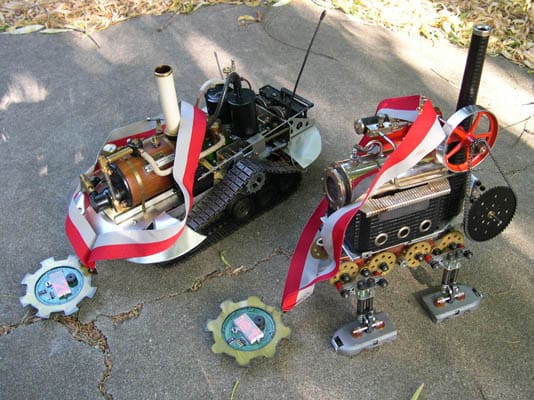 A robotic crab made of metal components with gears, wires, and tubes on a light-colored surface.