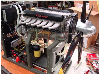 A photograph of an industrial engine, likely a Rolls-Royce Merlin, featuring intricate components.