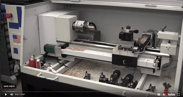 Lathe machine in industrial setting on gray background.