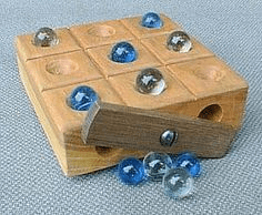 Wooden game board with 6 glass marbles on a gray background.