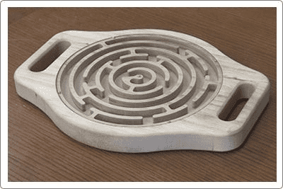 A white hexagonal tool with spiral design and two handles on a wooden surface.