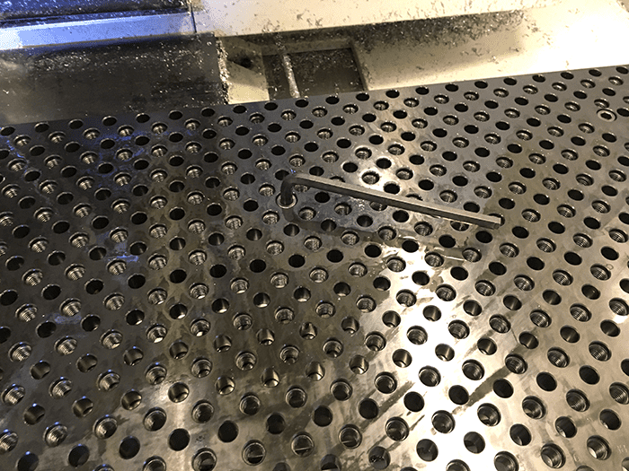 Dark-colored metal workbench with numerous circular holes.