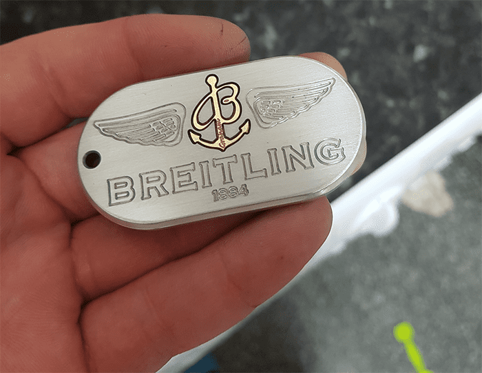Silver Breitling logo with wings on a dark gray background.