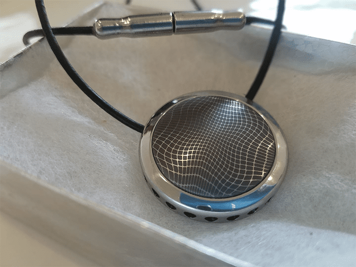 Silver object with spiderweb-like pattern and black cord.