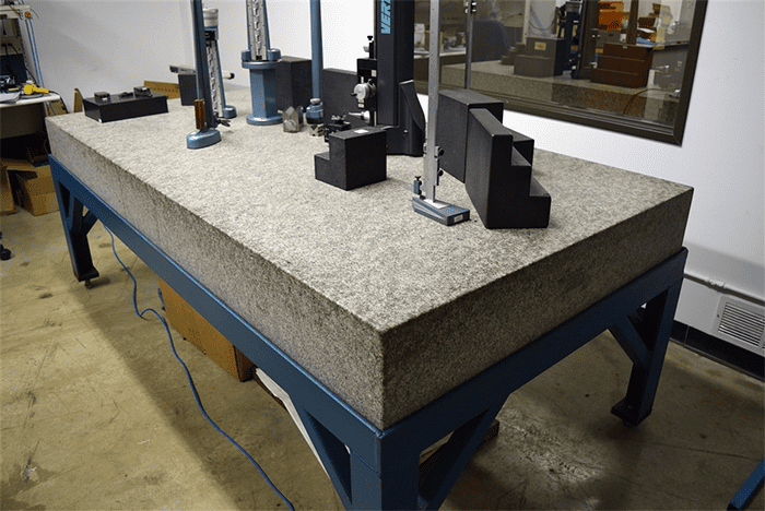 Large workbench with granite surface and various measurement tools.