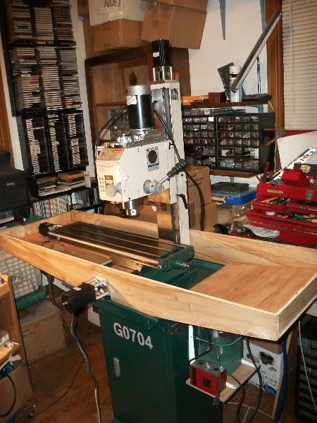 A workshop with a milling machine, drill press, and lathe, featuring various tools and in-progress projects.