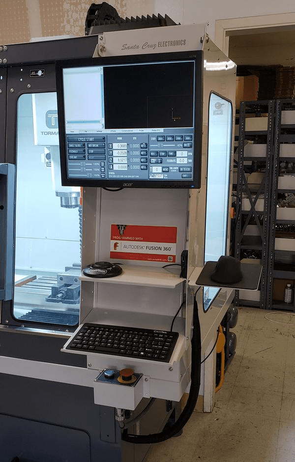 CNC machining center with computer monitor and keyboard in workshop factory setting.