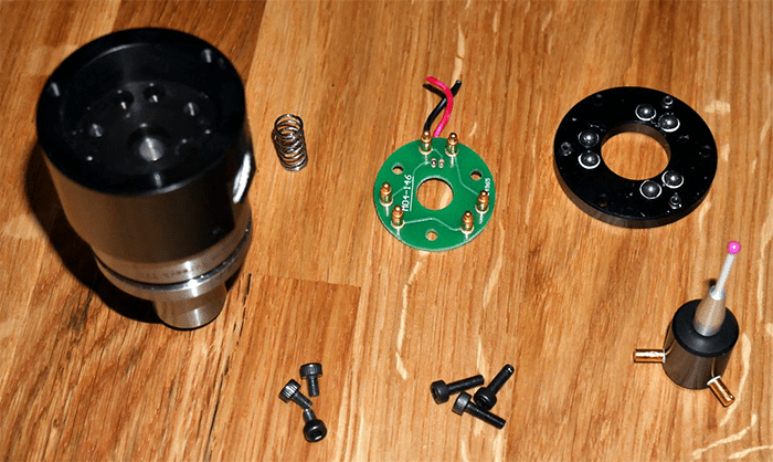 Machining parts and tools on a wooden workbench.