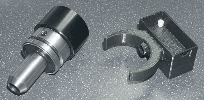 Mechanical components: cylindrical object, curved metal piece, rectangular block.