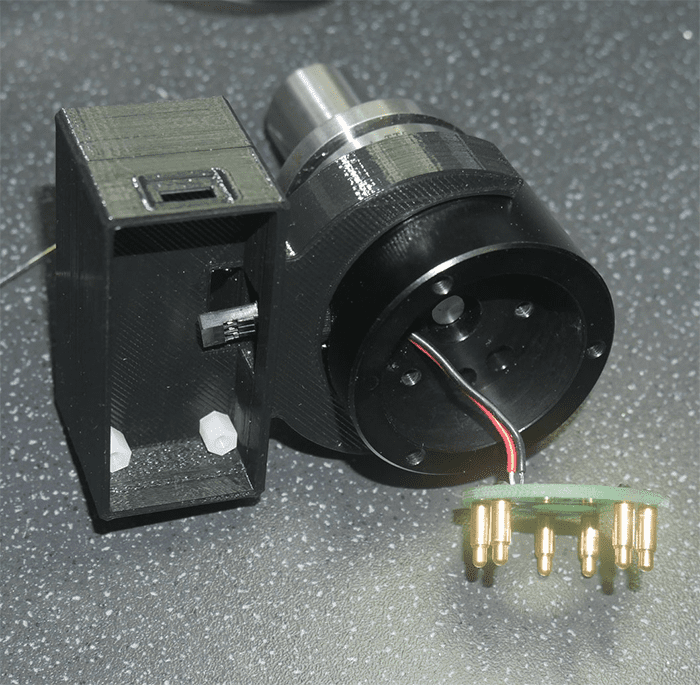 Black plastic cylinders with small openings and holes, bundled with wires and brass connectors.