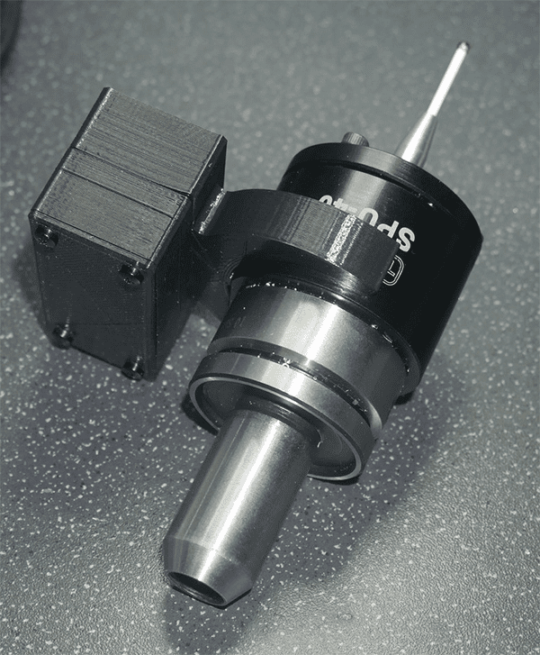 Black cylindrical machine tool with silver tip and small cube-shaped object.