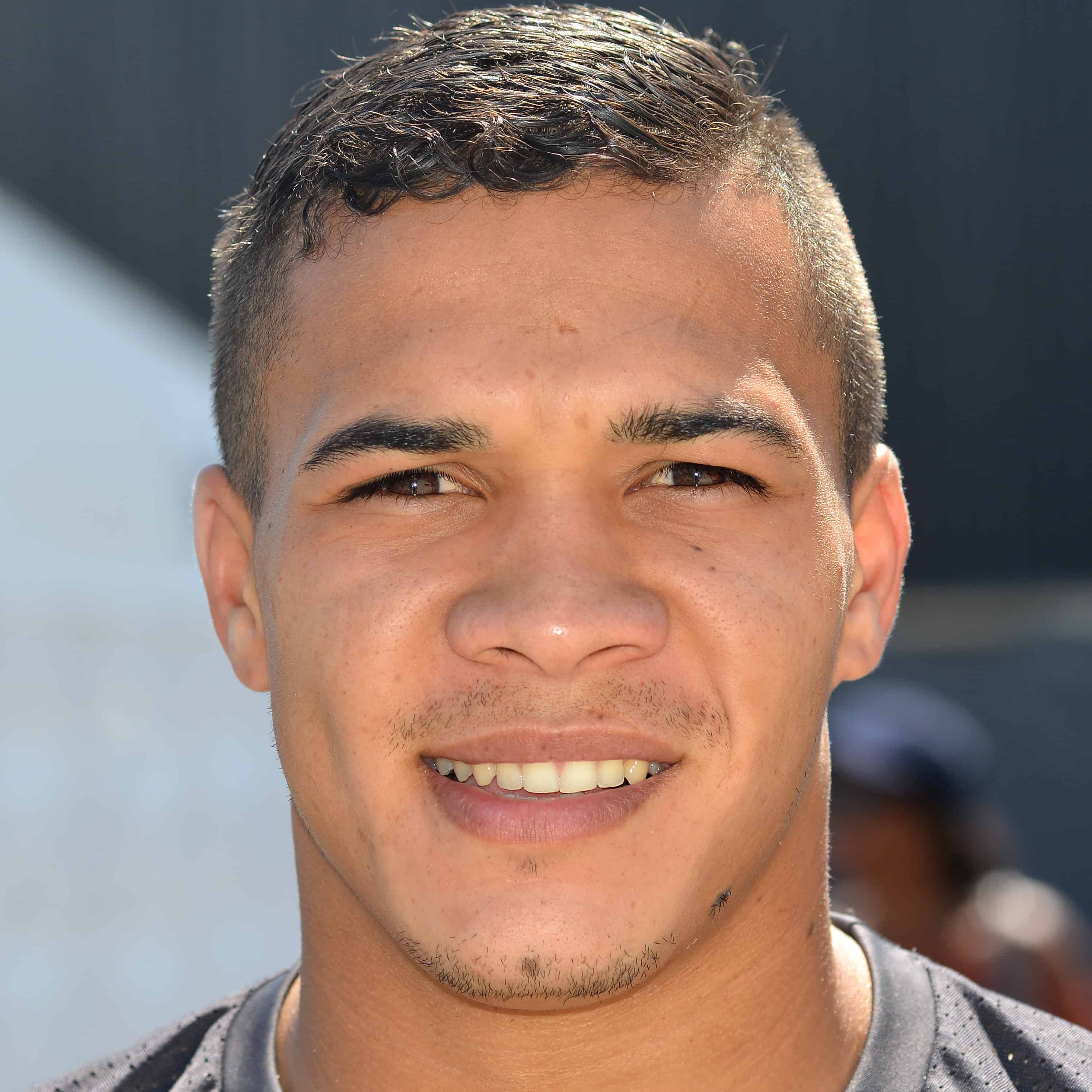 South African rugby player Cheslin Kolbe from the shoulders up, wearing a gray shirt in an outdoor setting.