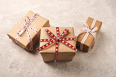 Three elegantly wrapped gifts in brown paper with red and white ribbon.