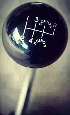 Black gearshift knob with white "3 County Prison" text and symbols in a circular pattern.