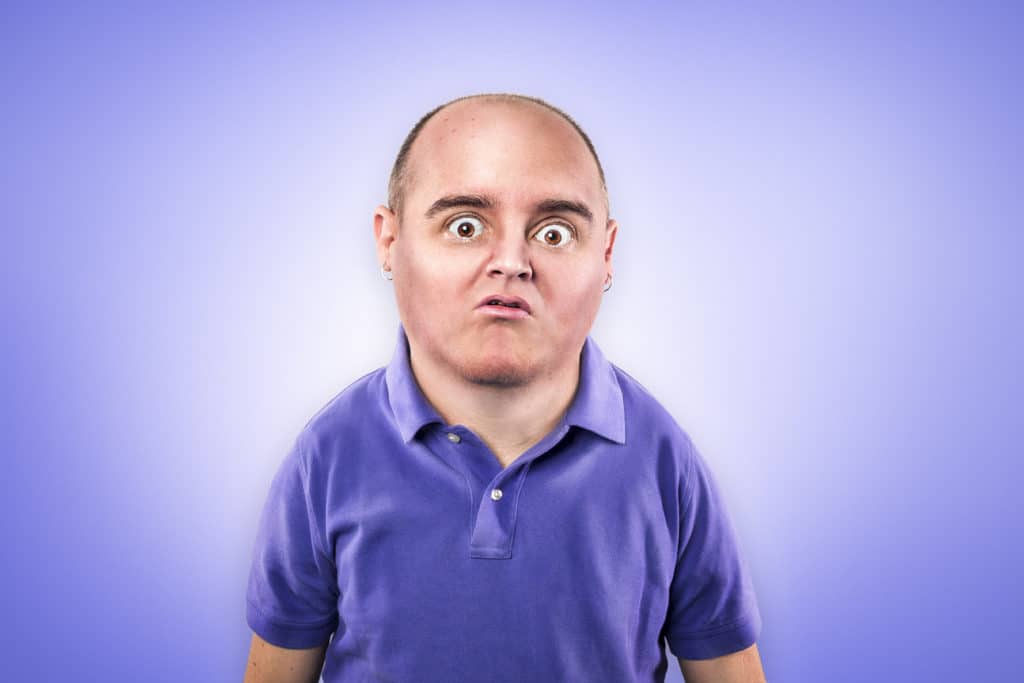 Man with startled expression, balding, goatee, wearing purple polo shirt.