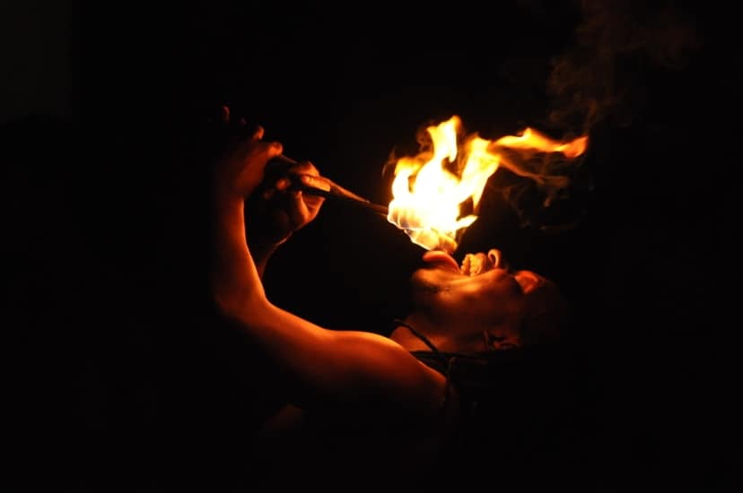 A person holding a lit torch in a dark environment with a bright yellow and orange flame.