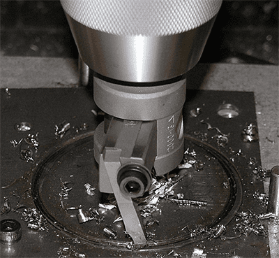 Metalworking tool, possibly drill bit or milling cutter, on workbench with metal shavings.