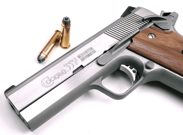 Silver Colt handgun with wooden grip and bullet on white background