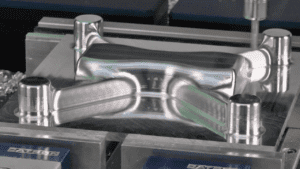 Silver cylindrical metal part with grooves and ridges, well-lit.