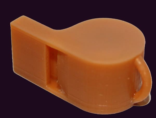 Orange plastic whistle with rounded body, short mouthpiece, and small loop handle on a dark gray background.