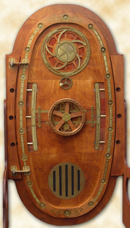 Large ornate wooden door with brass hardware, vintage submarine-style hatch design, set against blurred background.