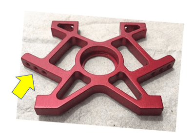 Red hexagonal object with circular hole and six cutouts.