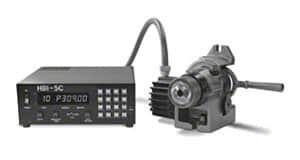 Black digital readout box connected to handheld measuring device with round knob and buttons.